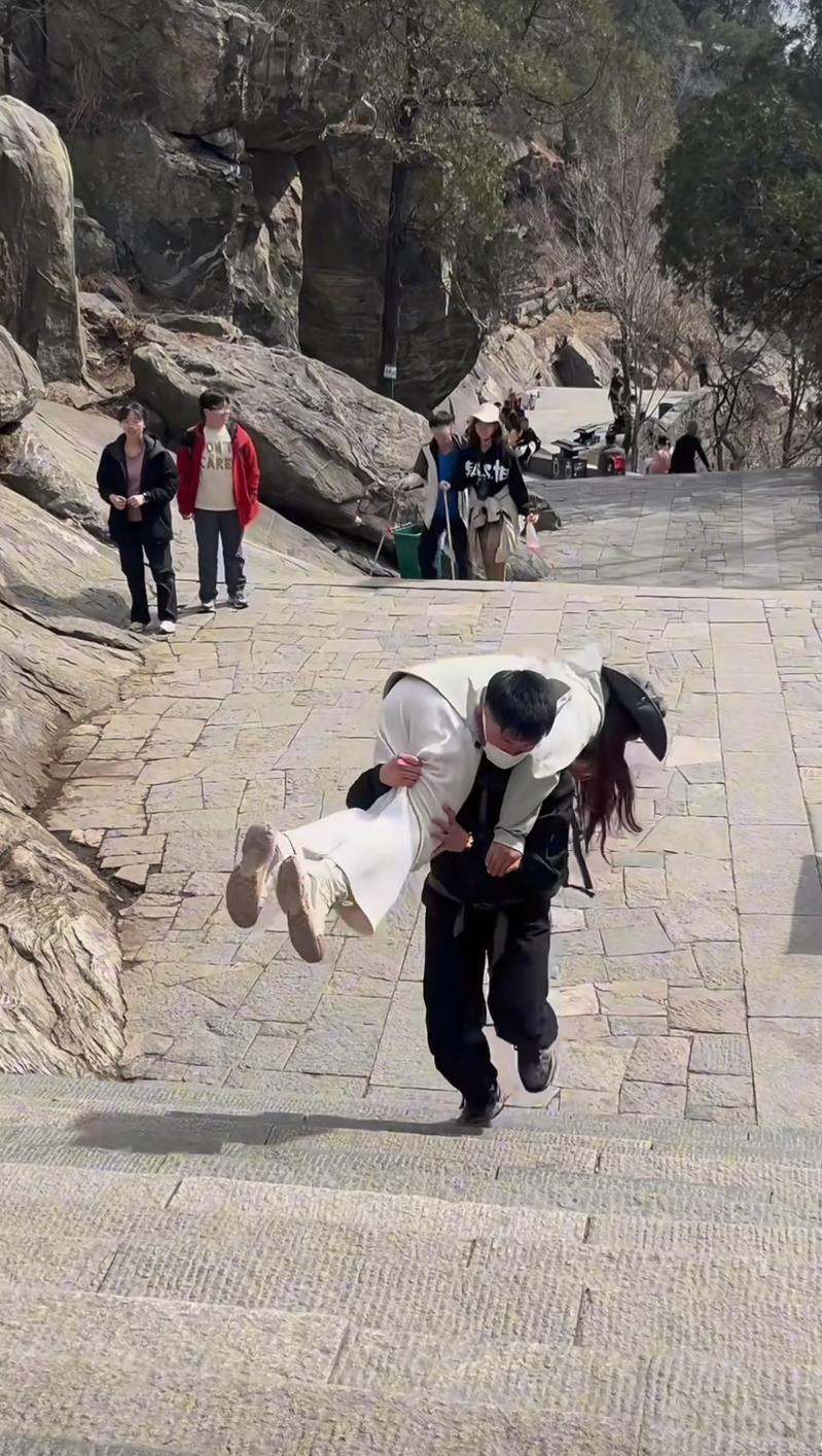 「陪爬泰山」已不只是「陪爬」，网上愈来愈多男性「陪爬者」将女性顾客背上山的视频。（视频截屏）
