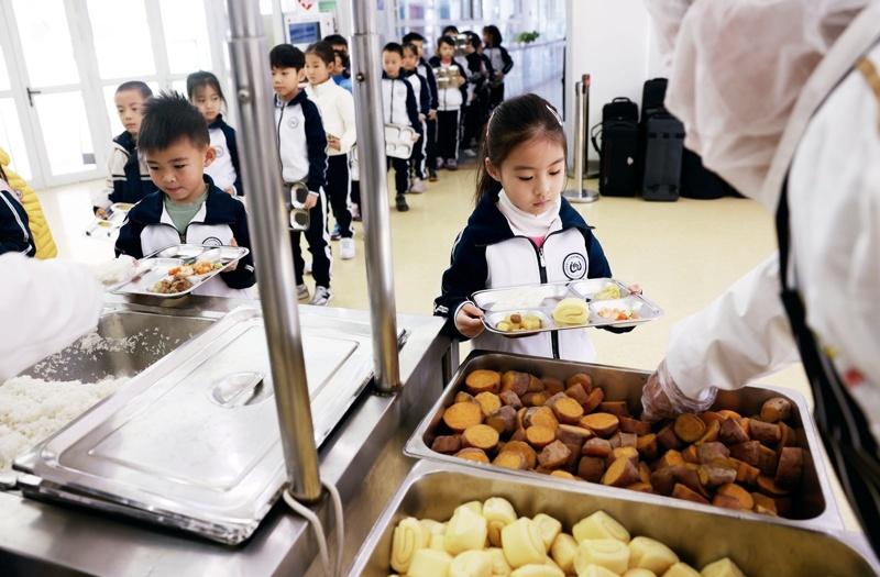 北京市第一六六中学附属校尉胡同小学的学生们排队取餐。(取材自新京报)