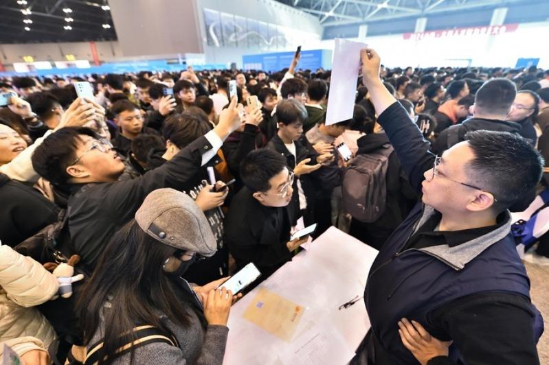 图为去年10月底,在山西太原一场征才大会上,求职者抢着用手机扫码获取企业的招聘消息。(中新社)