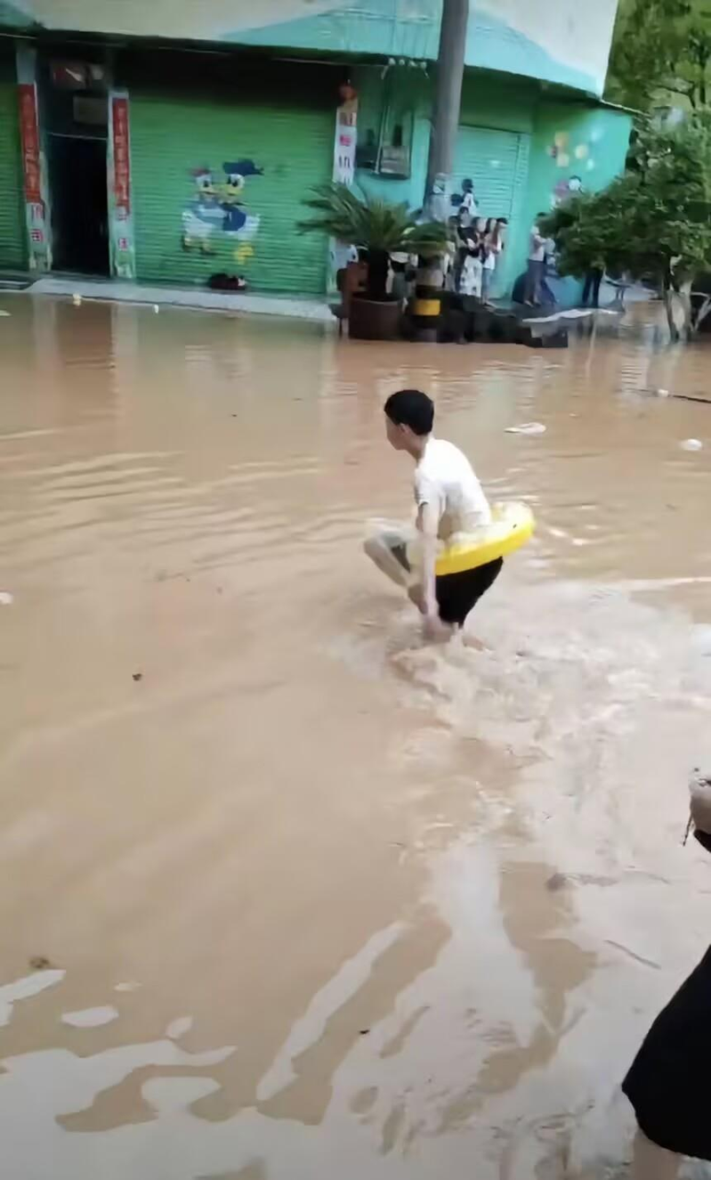 中考遇上暴雨,湖南龙山县一名学生只好游泳出行。(取材自极目新闻)