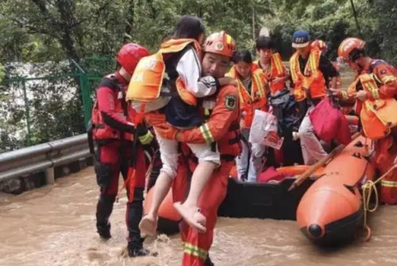 湘北、湘西北遭受特大暴雨袭击,已造成40余万人受灾。图为消防队员转移信道侗族自治县民众。(取材自北京日报)