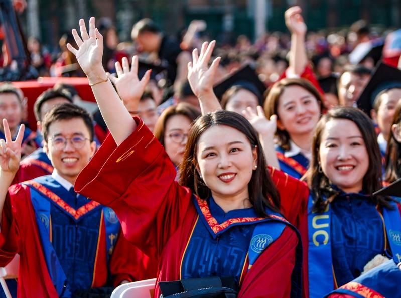 高校里女性同学数量逐年升高。图为人民大学毕业生开心的挥手。 (新华社)