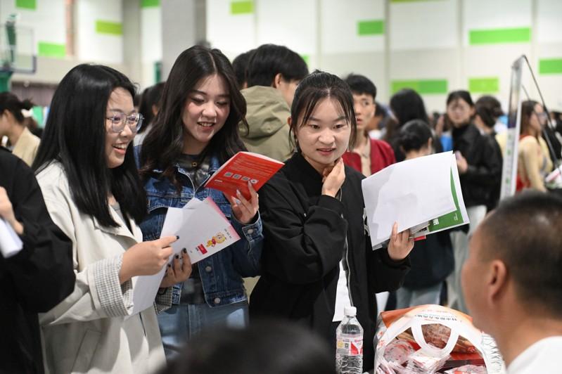 高校里女性同学数量逐年升高。图为人民大学毕业生开心的挥手。 (新华社)