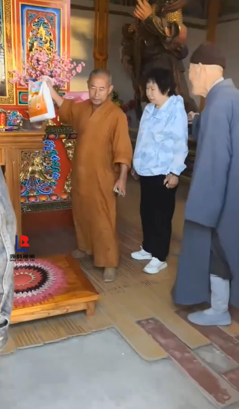 涉事僧人拿起老夫妇放在供桌上的米准备往外扔。(视频截屏)