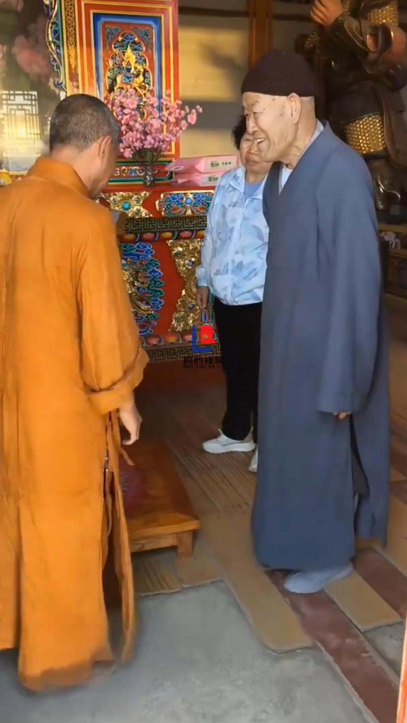 涉事僧人拿起老夫妇放在供桌上的米准备往外扔。(视频截屏)
