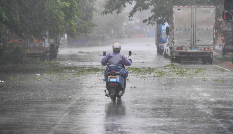 台风来袭,海南省乐东黎族自治县莺歌海镇,13日仍有民众冒着风雨骑车外出。(新华社)