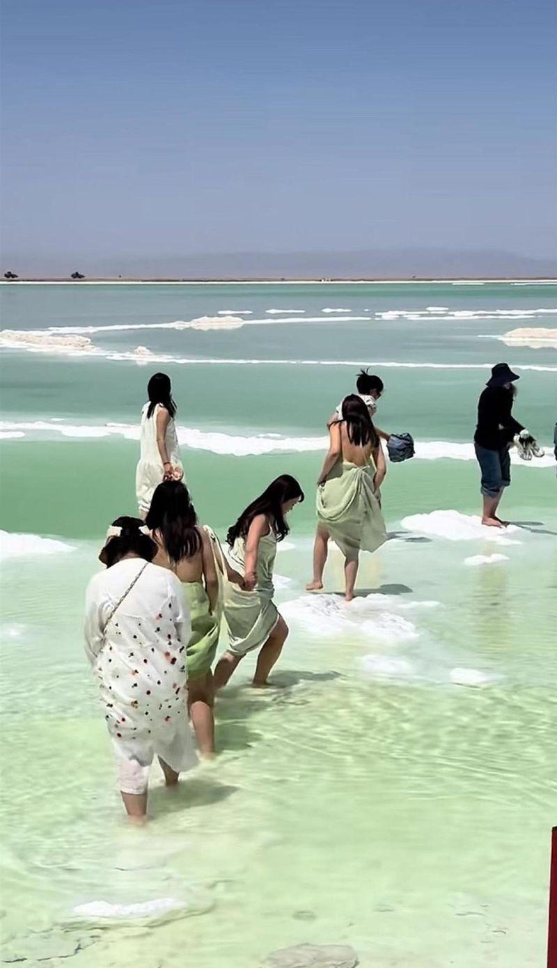 有游客赤脚进入察尔汗盐湖景区水域。(取材自极目新闻)