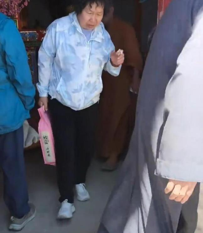 涉事僧人拿起老夫妇放在供桌上的米准备往外扔。(视频截屏)