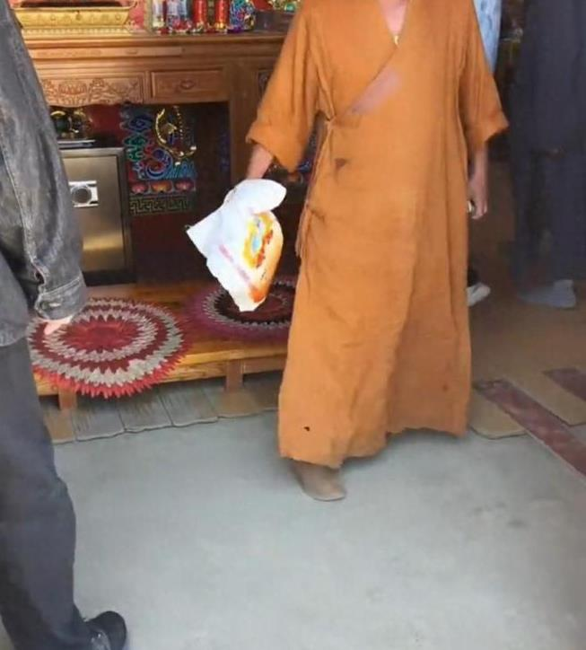 涉事僧人拿起老夫妇放在供桌上的米准备往外扔。(视频截屏)