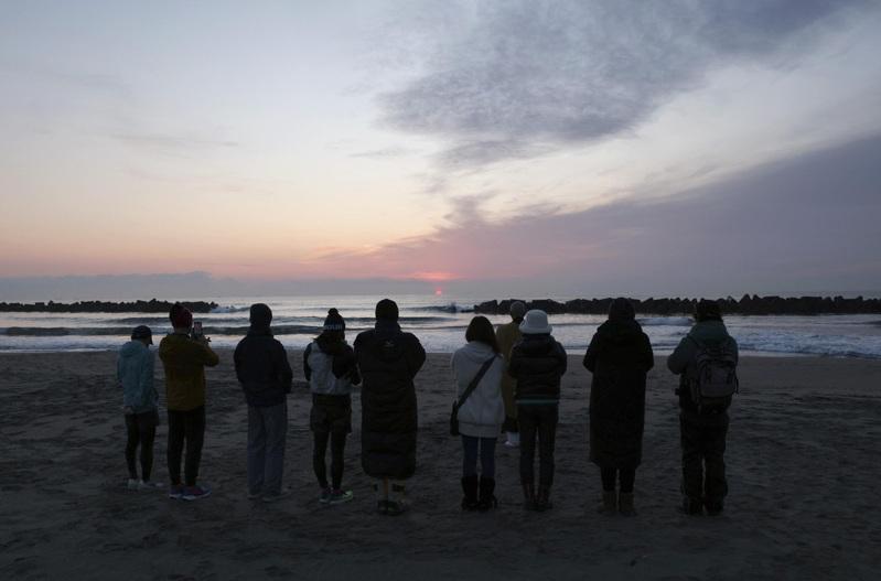 图为今年3月11日,日本宫城县仙台市一处海滩上,民众为2011年地震和海啸的罹难者祈祷。(路透)