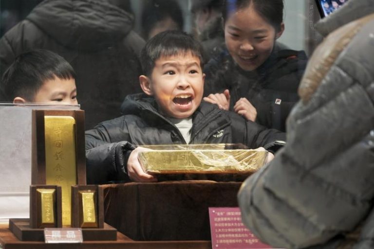 人行发新规，从8月起，现金买黄金达10万元必须上报；图为在北京一家金店内，小朋友搬起金条模型。 （中新社）