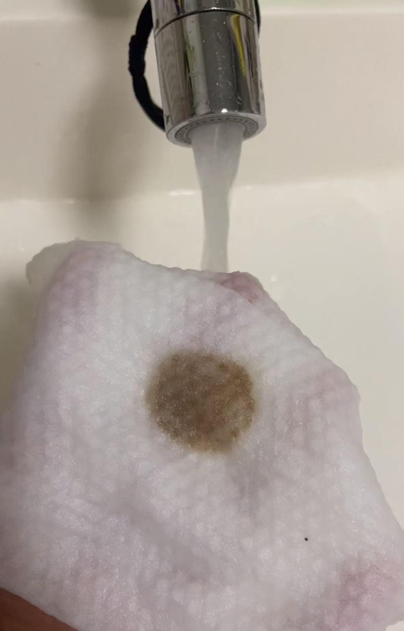 有居民用棉柔巾包裹住水龙头出水口，放水两分钟后，发现棉柔巾上留有深褐色的、疑似泥沙的沈淀物。(视频截屏)
