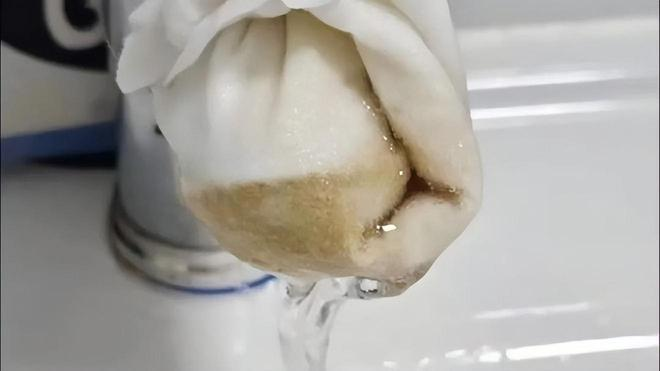 有居民用棉柔巾包裹住水龙头出水口,放水两分钟后,发现棉柔巾上留有深褐色的、疑似泥沙的沈淀物。(视频截屏)
