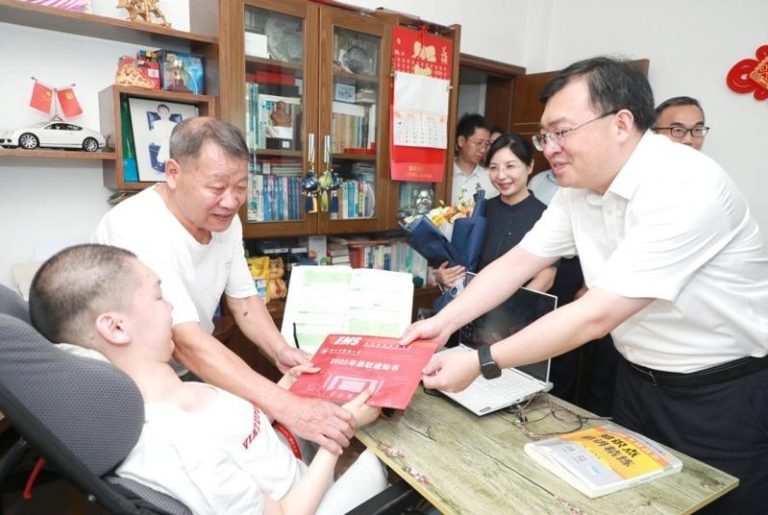 浙江中医药大学党委书记王斌（右）将录取通知书递到徐立芃（左）手中。(取材自潮新闻)