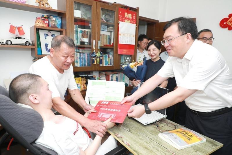 浙江中医药大学党委书记王斌(右)将录取通知书递到徐立芃(左)手中。(取材自潮新闻)
