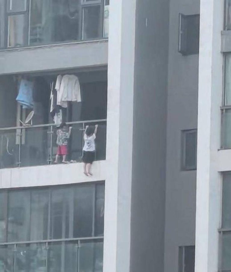 贵阳两名幼童在阳台外玩耍，视频拍摄者吓得连连惊呼。（视频截屏）