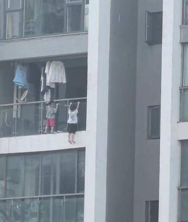 贵阳两名幼童在阳台外玩耍,视频拍摄者吓得连连惊呼。(视频截屏)