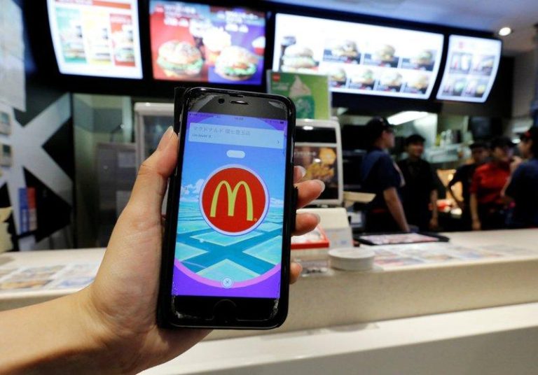 一名顾客在东京一家麦当劳分店，持手机秀出宝可梦App上的麦当劳标志。(路透数据照)