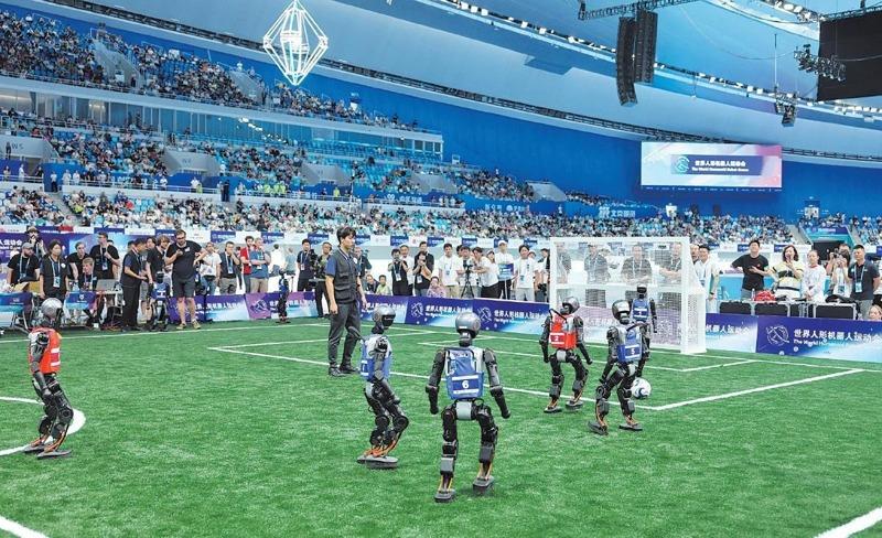 8月17日，2025世界人形机器人运动会足球赛项5V5决赛，清华大学火神队（红队）与对手拚抢中球出界。（取材自新京报）