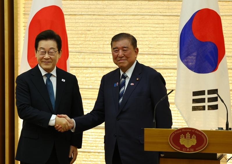 南韩总统李在明(左)23日访问东京,和日本首相石破茂(右)举行领袖会谈,会后召开共同记者会时两人微笑握手。(欧新社)
