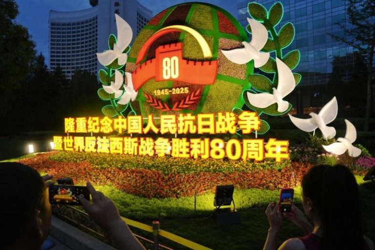 8月22日，亮灯的纪念抗战胜利80周年主题花坛扮靓北京长安街，吸引民众参观打卡。(中新社)