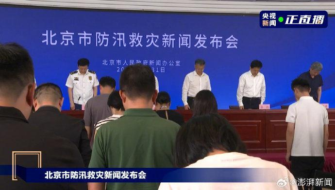 北京防汛救灾新闻发布会上，与会人员为罹难者默哀。（视频截屏）