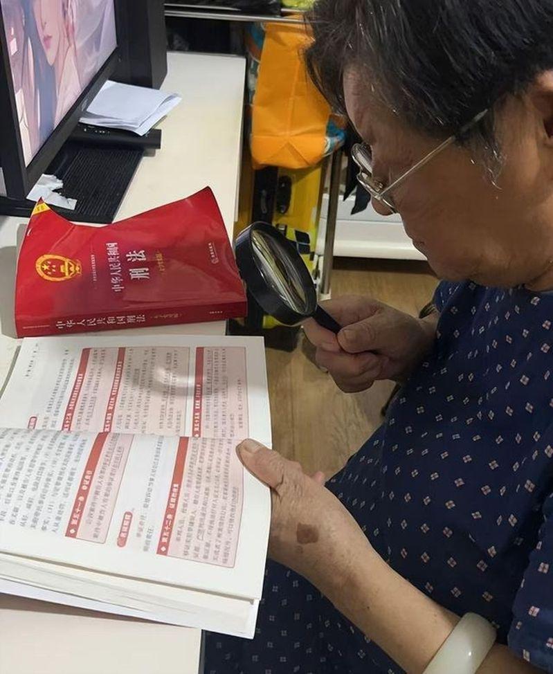 何婆婆拿放大镜学习法律知识。(取材自华商报大风新闻)