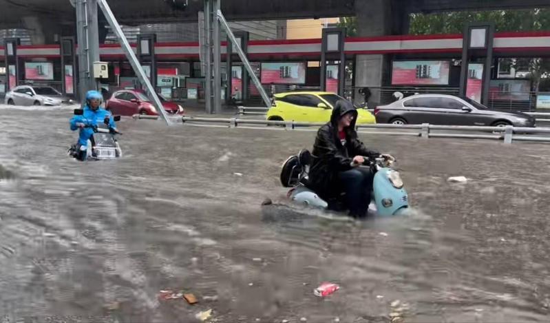 河南郑州7日暴雨,在一高架桥下,行人在齐大腿深的水里行走,有两轮电动车涉水而过。(取材自极目新闻)
