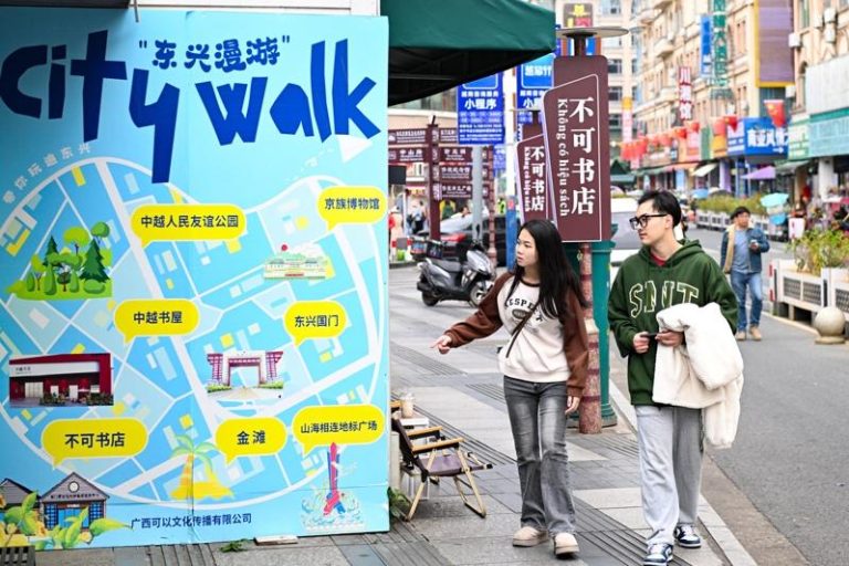 暑期外国游客在中国「小城游」升温。图为游客在广西东兴街头，关注「东兴漫游」地图。（新华社）