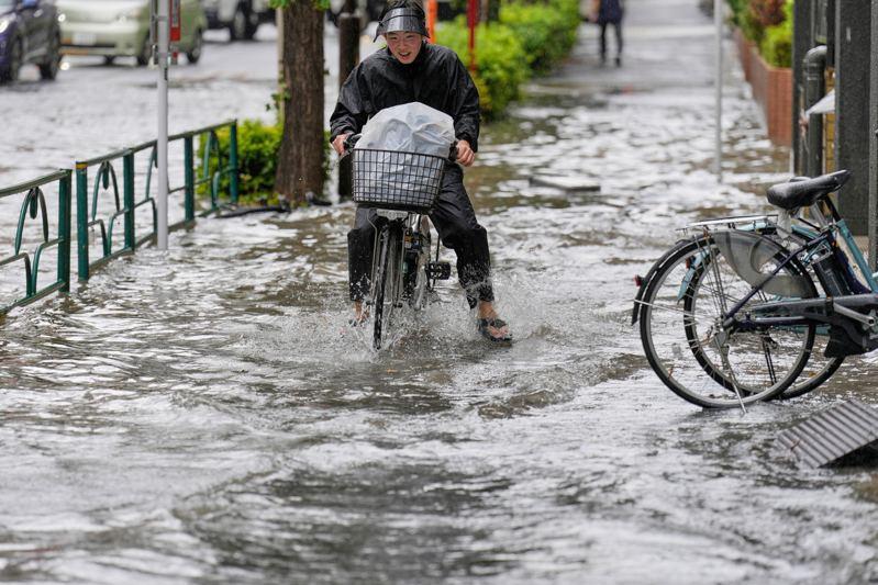 日本关东地区东京都、神奈川县等地11日下午暴雨成灾,一名男子骑单车通过淹水的东京街道。美联社