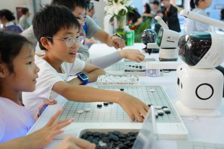 中国积极培养学生AI技能，北京1400多所中小学开设「人工智能通识课」。图为日前北京服贸会期间，小朋友和机器人下五子棋。（新华社）