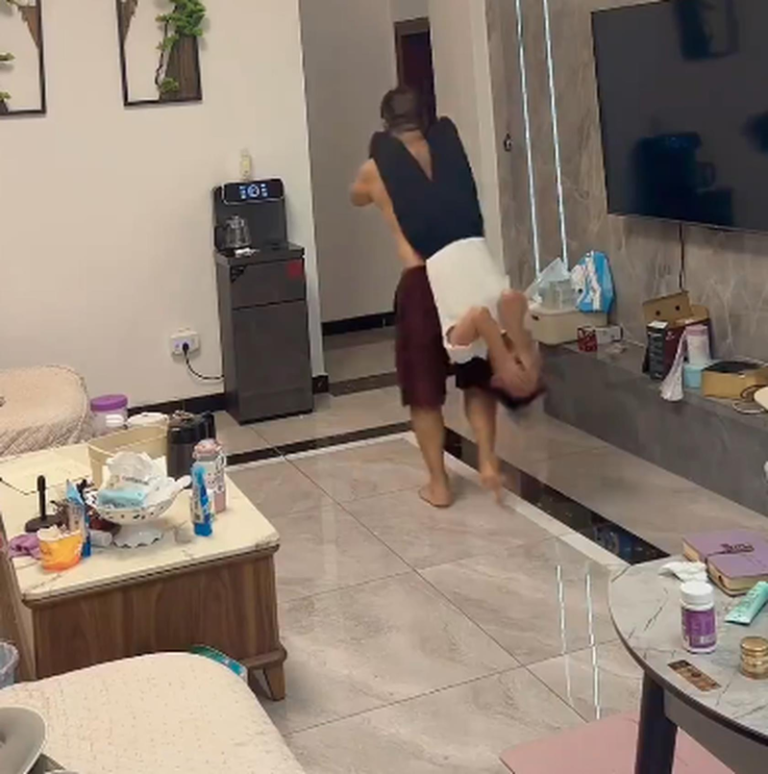 徐女士老公背着她倒立并不时走动，让她的身体能因震动排石。（视频截屏）