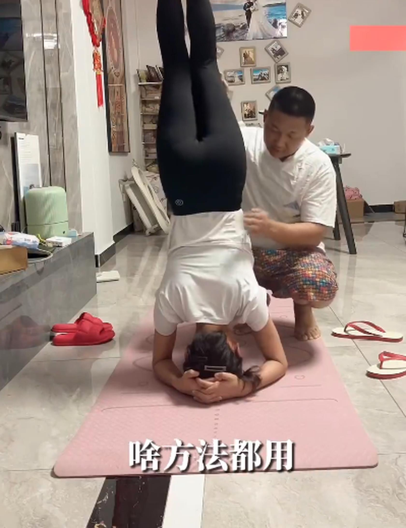 徐女士老公背着她倒立并不时走动，让她的身体能因震动排石。（视频截屏）