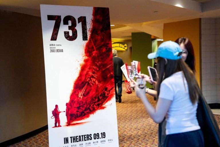 在美国纽约一家电影院，观众经过电影「731」的海报。(新华社)