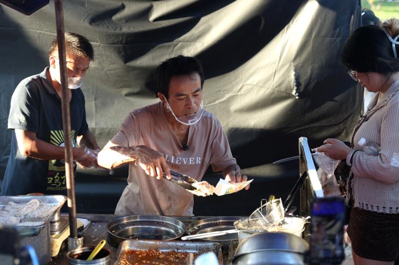 「鸡排哥」李俊永正在摊位前为顾客制作美食。(中新社)