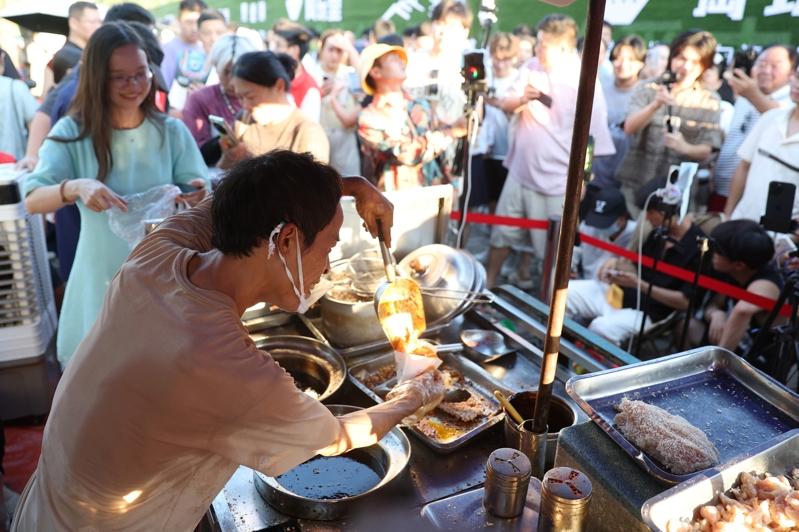 「鸡排哥」李俊永正在摊位前为顾客制作美食。(中新社)