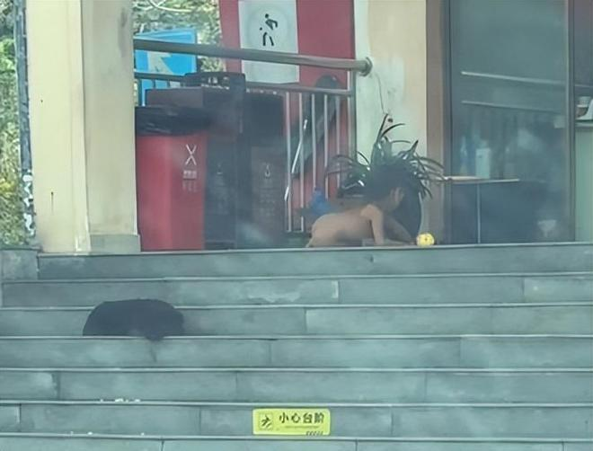 男童爬着在台阶上吃炒饭。(视频截屏)