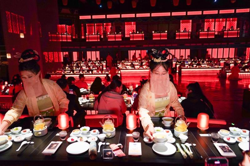 以大宋文化为创作背景的沉浸式宋文化主题餐秀「清明上河·宋宴」日前在河南开封清明上河园上演，吸引民众前来体验。图为裸眼3D光影呈现的古代画面吸引顾客观看。（中新社）