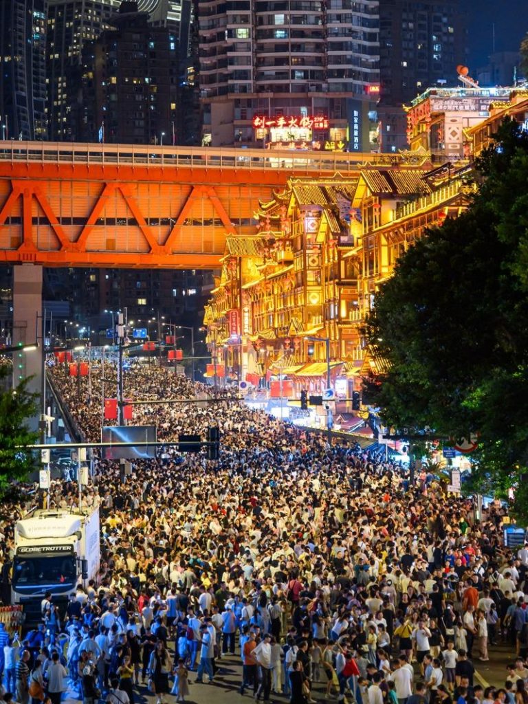 中国黄金周的10月3日晚，重庆洪崖洞的数万游客挤满马路，人与灯光交互辉映。（中新社）
