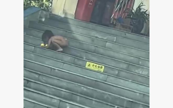 男童爬着在台阶上吃炒饭。(视频截屏)