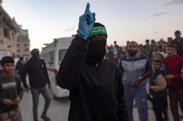 巴勒斯坦人注视着哈玛斯军「卡萨姆旅」成员，从加萨南部汗尤尼斯哈马德市区域的一处地道中，擡出一名以色列人质的遗体。(欧新社)