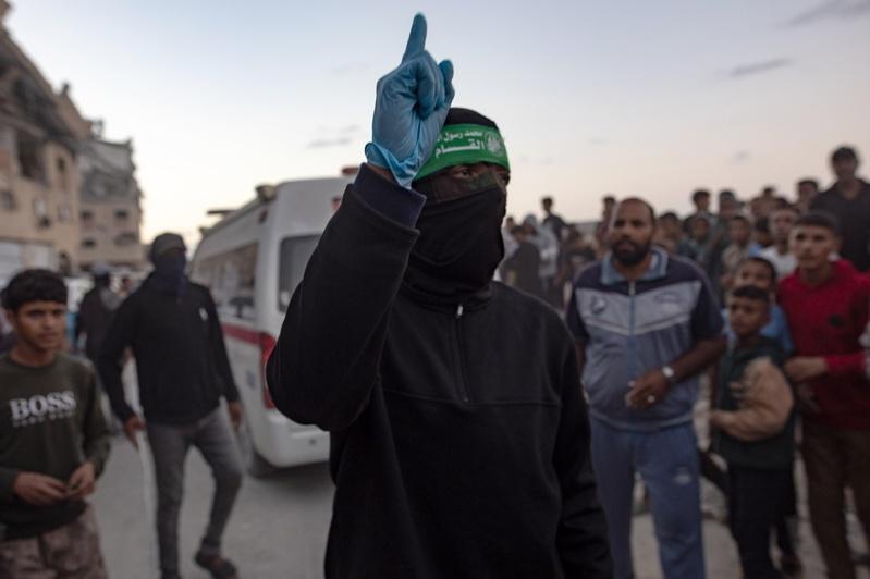 巴勒斯坦人注视着哈玛斯军「卡萨姆旅」成员，从加萨南部汗尤尼斯哈马德市区域的一处地道中，擡出一名以色列人质的遗体。(欧新社)