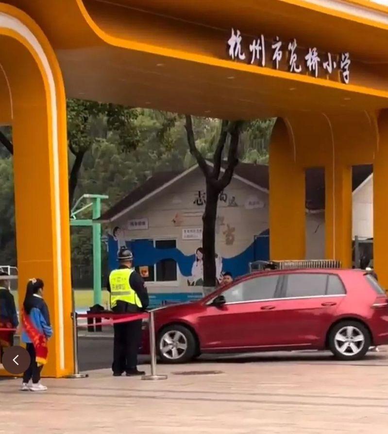 杭州市笕桥小学校门口有身揹绶带的小学生向开车进学校的老师敬礼。(取材自大风新闻)