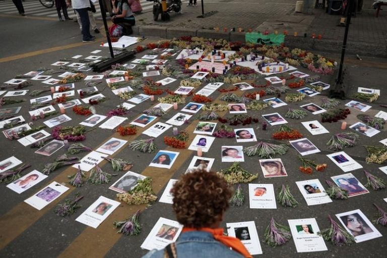 联国:全球每10分钟1女性遇害 多由家人、伴侣下手 2025年11月25日,在哥伦比亚波哥大,一名示威者在纪念消除对妇女的暴力行为国际日的抗议活动中,观看被杀害女性受害者的照片。(路透)