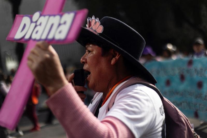 2025年11月25日,在哥伦比亚波哥大,一名示威者在纪念消除对妇女的暴力行为国际日的抗议活动中,观看被杀害女性受害者的照片。(路透)