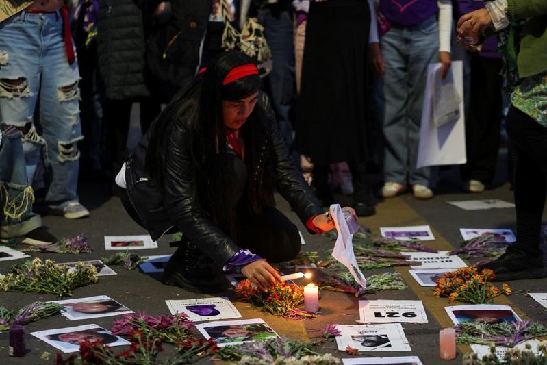 2025年11月25日,在哥伦比亚波哥大,一名示威者在纪念消除对妇女的暴力行为国际日的抗议活动中,观看被杀害女性受害者的照片。(路透)