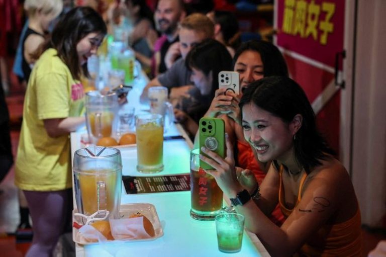 日本女性健身主题酒吧「筋肉女子」在网上爆红，来自中国大陆的女顾客拿起手机拍摄工作人员表演。路透