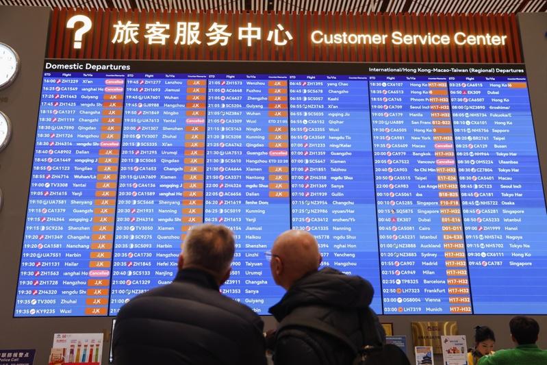 中国政府祭出「限游令」后,往返日本与中国的航班停飞情况持续扩大。图为在北京首都机场查看航班的旅客。(欧新社)