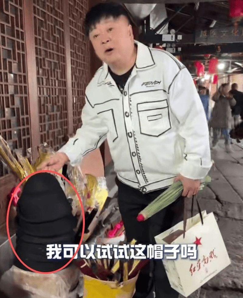 洪剑涛在浙江绍兴安昌古镇想试戴帽子,商家表示要收钱。(视频截屏)