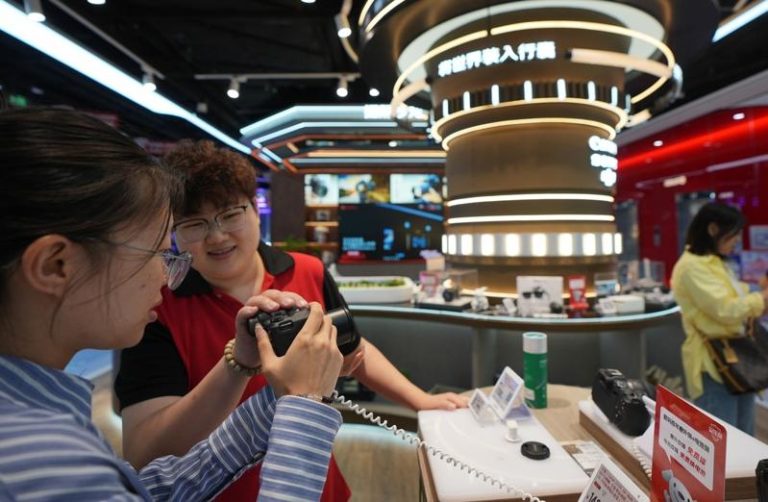 京东海外布局再下一城 拿下德国零售巨头59.8%控股权 中国电商巨头京东近年来持续将海外布局扩大。图为大连京东MALL商场的销售专员向顾客推荐照相机。(新华社)